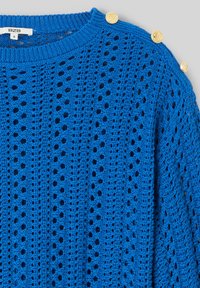 Pull en maille crochetée bleu vif avec un motif ajouré vertical et trois boutons décoratifs dorés le long de la couture d'épaule.