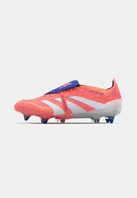 Botín de fútbol de un vibrante color rosa y naranja con una correa azul, franjas diagonales blancas y una suela translúcida con tacos azules y rojos.