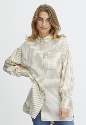 Striped button-up shirt in cream and beige, featuring a patch pocket. Textured fabric, relaxed fit, and long sleeves with button cuffs.