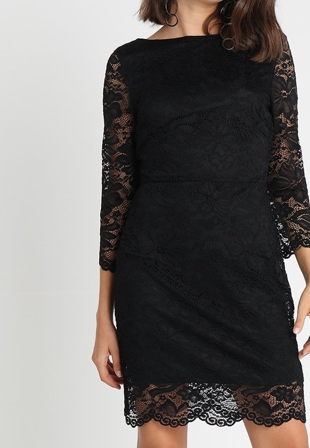 Svart spetsklänning med trekvartslånga ärmar, blommönster, vågig kant och en figurnära siluett. Texturerad tyg ger djup.