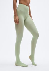 Κολάν με ψηλή μέση σε ανοιχτό πράσινο χρώμα, με λεία, ελαστική υφή και χωρίς κάλυμμα στα πόδια, κατάλληλο για διάφορες καθημερινές ή αθλητικές εμφανίσεις.