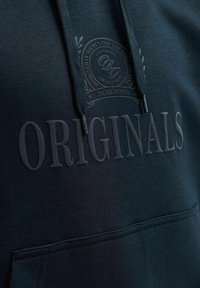 Σκούφο μπλε φούτερ με ανυψωμένο κείμενο «"ORIGINALS"» και κυκλικό λογότυπο πάνω με γράμματα «"Jack & Jones Copenhagen"» στην περιοχή του στήθους.