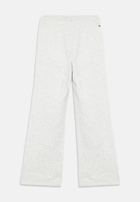 Grå joggebukser med et mykt, teksturert stoff. Løs passform, elastisk midje og en liten logo på siden. Ingen synlige mønstre eller detaljer.
