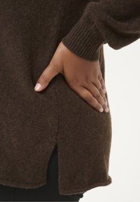 Bruine gebreide trui van zacht, gestructureerd materiaal met geribde mouwen en zijsplitten voor extra bewegingsvrijheid.