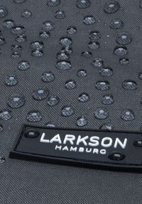Vattentåligt svart tyg med droppar, med en rektangulär svart etikett med "LARKSON HAMBURG" i vit text.