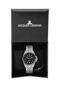 Reloj de acero inoxidable plateado con esfera negra, bisel giratorio y acentos azules en una caja negra abierta con el logo de "Jacques Lemans".