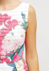 Robe florale à la coupe ajustée avec des rayures horizontales, principalement en blanc, rose et vert, en tissu texturé avec des motifs de feuilles.