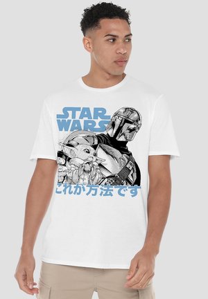 Man wearing white T-shirt with black-and-white Mandalorian and Baby Yoda illustration, blue "Star Wars" text, and Japanese characters below.