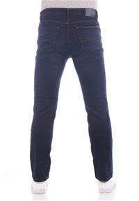Jeans de mezclilla azul oscuro con corte recto, que cuentan con bolsillos traseros y detalles de costura sutiles. Llevados con zapatillas blancas.