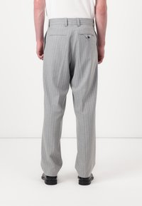 Gray pinstriped trousers with a tailored fit, featuring two back pockets, belt loops, and a textured fabric. Worn with black shoes.