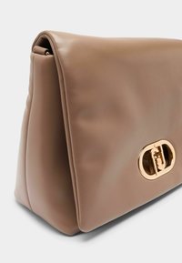 Grande borsa a mano in pelle marrone con texture liscia, caratterizzata da una prominente chiusura ovale dorata e una forma strutturata.