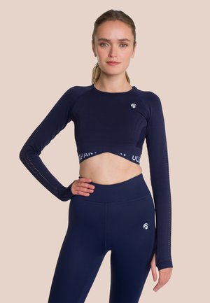 Marineblauwe lange mouwen sportieve crop top met mesh-details op de mouwen en logo. Gecombineerd met hoge taille marineblauwe leggings met een gladde textuur.