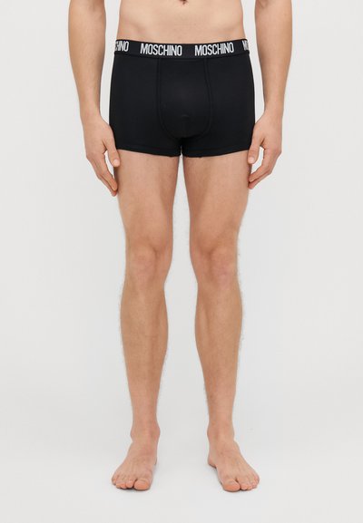Musta bokserilühikesed, mis on valmistatud pehmest kangast, omavad erilist sobivust, lameõmblusi ning kontrastset valget "MOSCHINO" logo vöökoht.