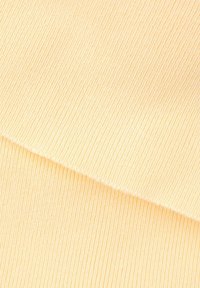 Gros plan sur un tissu en maille côtelée douce de couleur jaune pâle avec un pli diagonal visible.