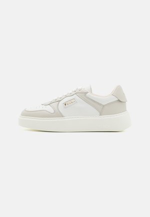 Fehér és bézs sneaker bőr és szintetikus anyagból. Kerek orr, perforált díszítések, fűzős záródás és vastag fehér talp. Logó részlet.