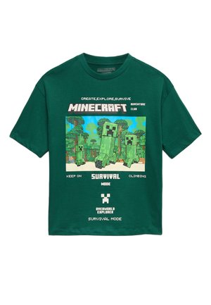 Mørkegrøn T-shirt med Minecraft Creeper-figurer i en pixeleret skov, med tekst om overlevelsesmode og udforskning.