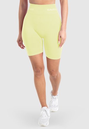 Geel hoogtijde fietsbroekje van rekbaar materiaal, met een strakke pasvorm en een elastische tailleband met de tekst "SMILE" in het wit.