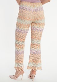 Kant flared broek met een veelkleurig zigzagpatroon in pastelkleuren van oranje, lavendel en groen, met golvende zoomdetails.