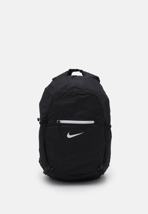 Sac à dos Nike noir avec poche avant zippée, logo Swoosh blanc et poignée de transport supérieure sur fond uni.