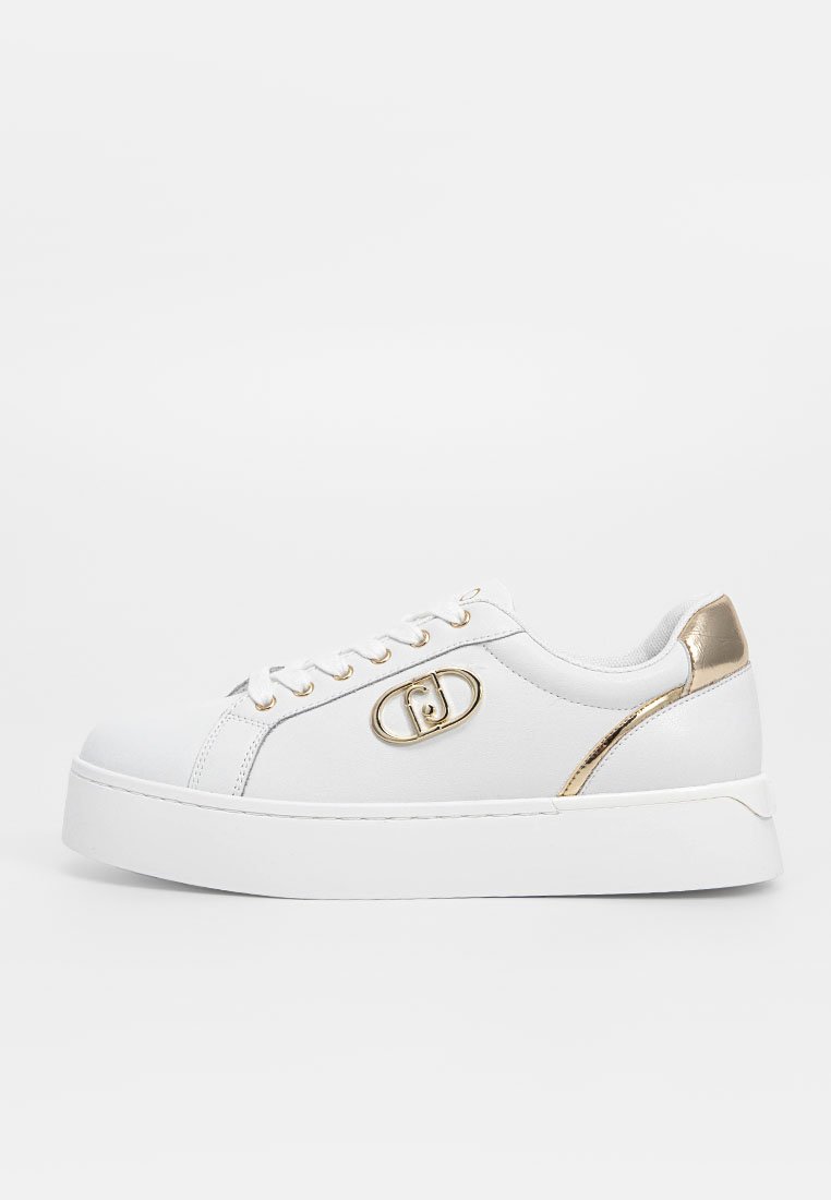Witte sneaker met een gladde textuur, gouden accent op de hak, cirkelvormig logo-detail en een witte vetersluiting op een dikke zool.