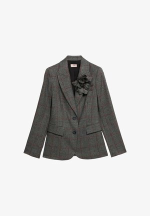 Blazer de cuadros gris con líneas rojas, dos botones, bolsillos de solapa y una flor de tela texturizada prendida en la solapa izquierda.