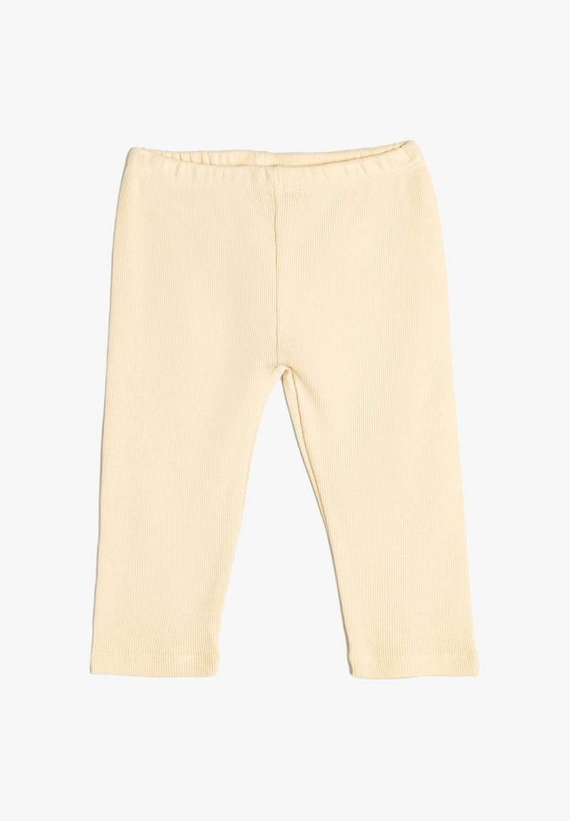 Leggings de canalé de color beige claro con una cinturilla elástica, diseño ajustado y sin herrajes ni acentos visibles. Textura suave y corte hasta los tobillos.