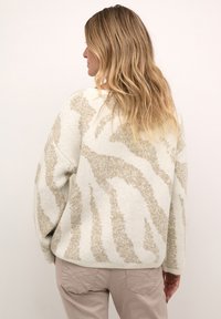 Maglione a righe beige e crema con una vestibilità ampia, realizzato in materiale morbido, caratterizzato da maniche larghe e orlo a coste.