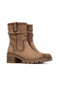 Botas de tobillo de ante marrón con un diseño holgado, tacón grueso robusto y una correa decorativa con un detalle de botón de metal. Suela de goma texturizada.