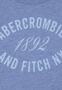 Modra heather majica s kapuco z belim napisom "ABERCROMBIE & FITCH NY" in "1892," okrogla zasnova, mehak tekstura in rebrast ovratnik.