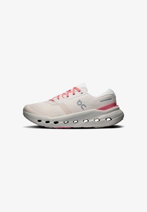 Chaussure de course rose clair et blanche avec des lacets roses, des trous de ventilation dans la semelle intermédiaire et le logo de la marque sur le côté.