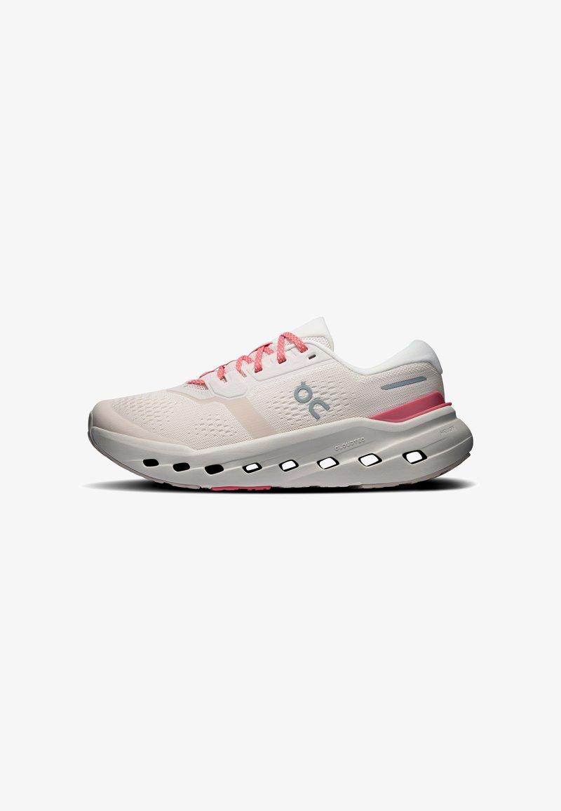 Chaussure de course rose clair et blanche avec des lacets roses, des trous de ventilation dans la semelle intermédiaire et le logo de la marque sur le côté.