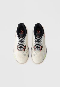 Beige sportcipő, textúrált felsőrésszel, fekete betétekkel, fényvisszaverő fűzőkkel és neon zöld részletekkel a talpon. Oldalán logó található.