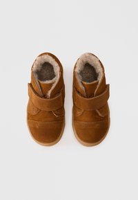 Braune Wildleder-Stiefel für Kleinkinder mit einem weichen, flauschigen Futter und verstellbarem Klettverschluss. Verfügt über eine abgerundete Zehenpartie und eine Gummisohle für besseren Halt.