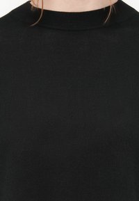 Maglione nero a maglia con texture a coste e un collo alto e rotondo. Il tessuto appare morbido e aderente.