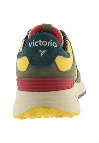Zapatilla deportiva de gamuza verde con detalles en amarillo y rojo. Cuenta con una suela acolchada, cordones con patrón en blanco y negro, y un logo en la parte trasera.