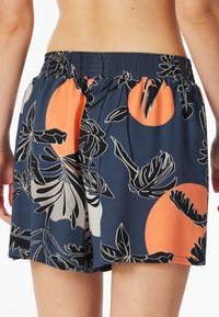 Šortky s modrým květinovým potiskem a oranžovými kruhy, elastickým pasem a lehkým, hladkým materiálem s volnějším střihem.