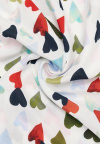 Tessuto bianco con un motivo di cuori sovrapposte in vari colori, tra cui rosso, blu, verde e nero, con una superficie liscia.