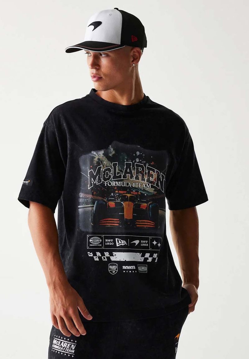Czarna bawełniana koszulka z grafiką zespołu Formuły 1 McLaren, okrągły dekolt, krótkie rękawy oraz akcenty logo w białym i pomarańczowym kolorze.