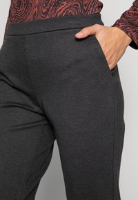 Grå byxor i ankellängd gjorda av mjukt tyg, med en sidoficka och en slät midjebandsdesign. Minimalistisk look med en ren finish.
