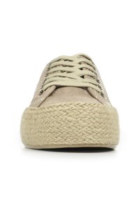Chaussure en toile beige avec un bout rond, une surface texturée et une semelle tissée ressemblant à du jute. Équipée de lacets plats et d'œillets en métal.