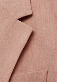 Tissu rose clair avec une texture lisse et un motif de tissage subtil ; comprend des détails de col et de poches sur un vêtement ajusté.