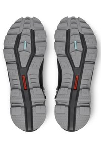 Sole of black athletic shoes featuring a gray textured rubber outsole with deep treads, accentuated by blue and red details.