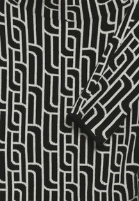 Tejido de punto en blanco y negro con un patrón geométrico de líneas entrelazadas; textura suave con un fuerte contraste entre los colores.