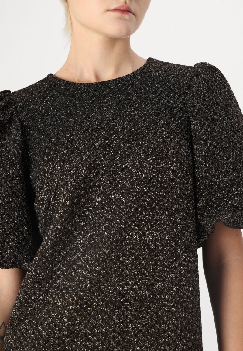 Czarna bluzka z fakturowanego materiału, z bufkami na rękawach i okrągłym dekoltem, z subtelnym, błyszczącym wzorem na całej powierzchni tkaniny.