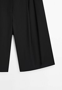 Sorte skræddersyede shorts lavet af glat stof, med en vidbenet pasform, rene linjer og uden synlige lommer eller hardware.