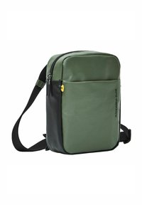 Bolso bandolera verde y negro con material sintético texturizado, compartimentos con cierre, correa ajustable y herrajes de acento amarillos.