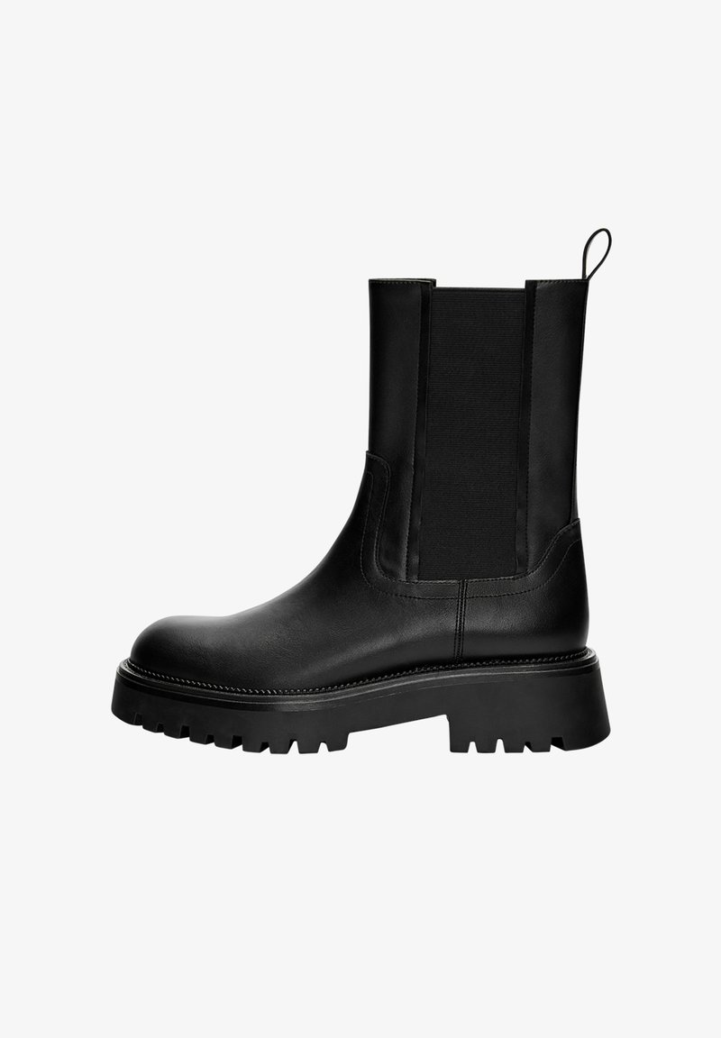Bottine Chelsea en cuir noir mi-mollet avec panneaux latéraux élastiques, languette à l'arrière, semelle épaisse et bout arrondi.