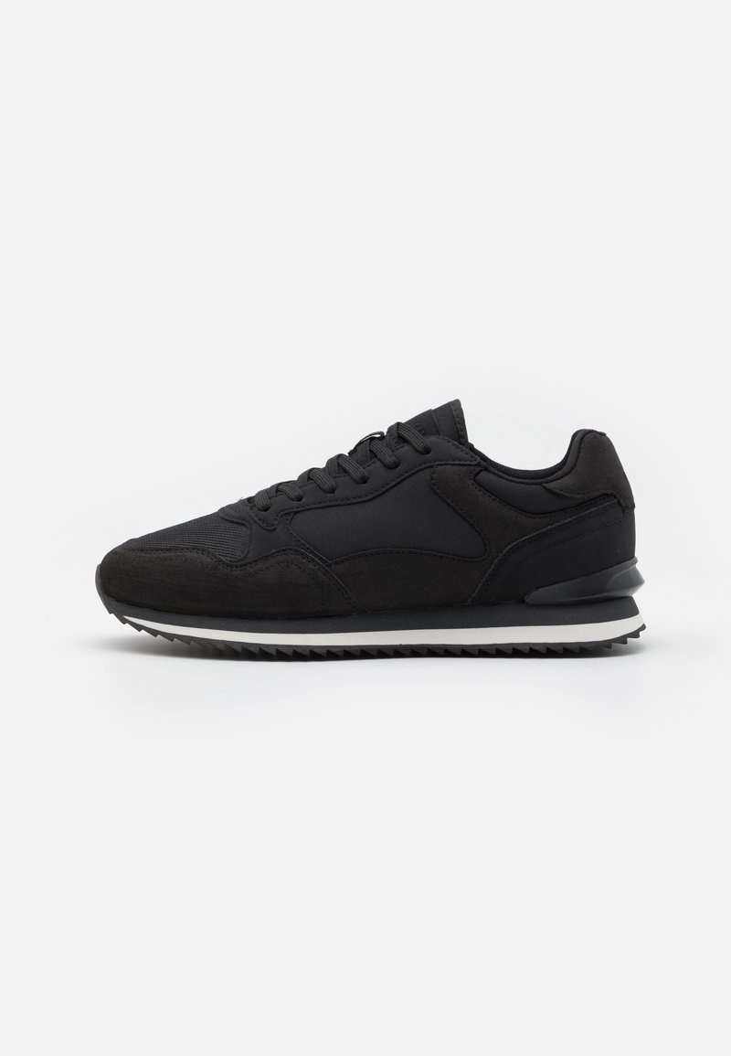 Black athletic sneaker featuring a mix of textured suede and synthetic materials, round toe, flat laces, and a cushioned white midsole.