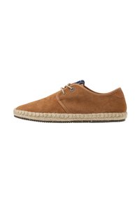 Zapatos de ante marrón con punta afilada, suela de cuerda más clara en contraste y cierre de cordones. La parte superior presenta una textura suave y un detalle mínimo.