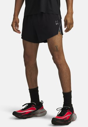 Black athletic shorts with side slits, paired with red and black sneakers featuring a textured sole and reflective accents.